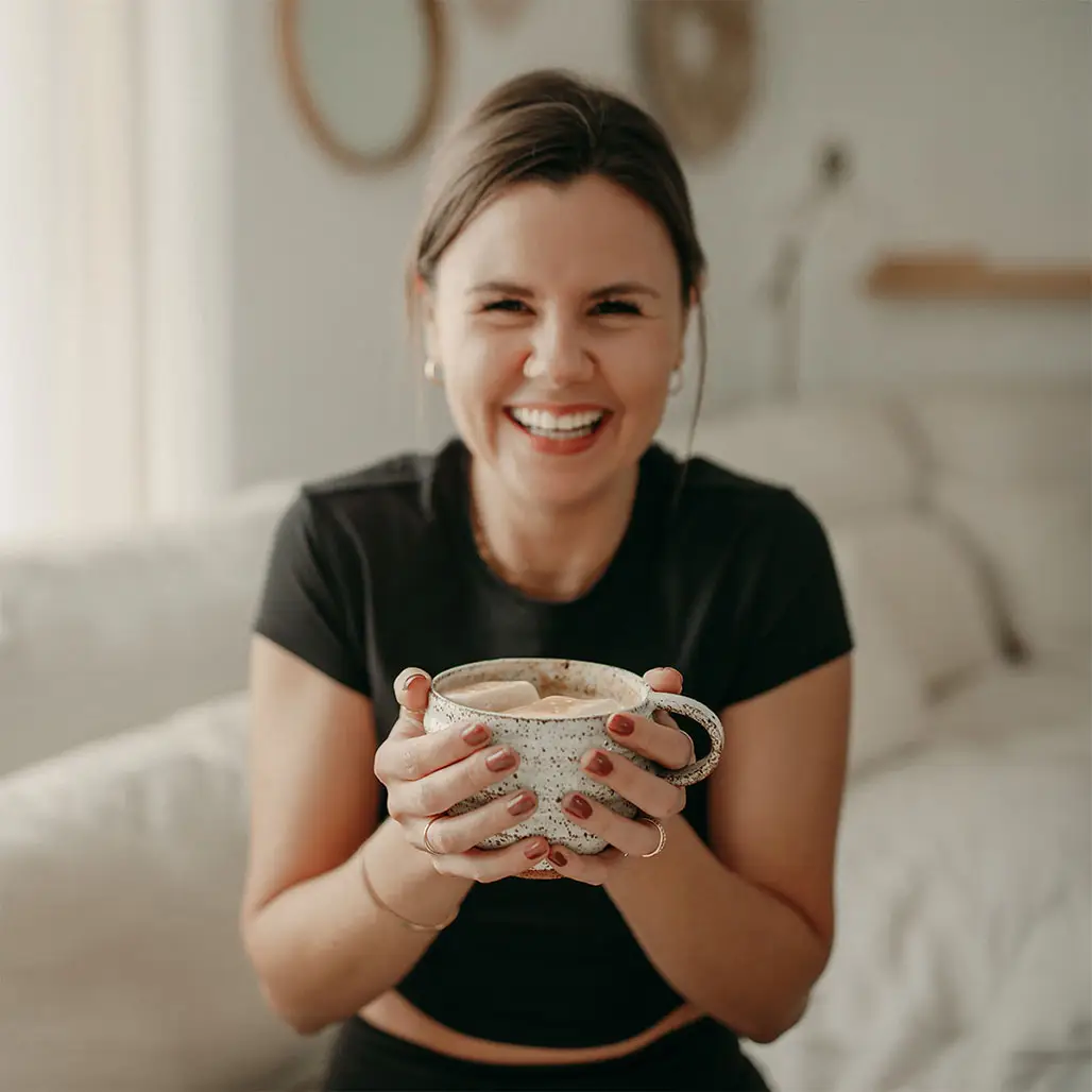 Michelle laughing and holding a cup of coffee